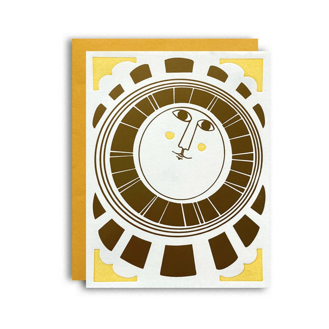 white card with yellow envelope featuring a gold sun with a face surrounded by a gold block design and yellow corners