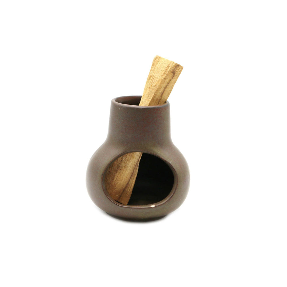 front view of a brown ceramic mini chimney with a stick of palo santo in it