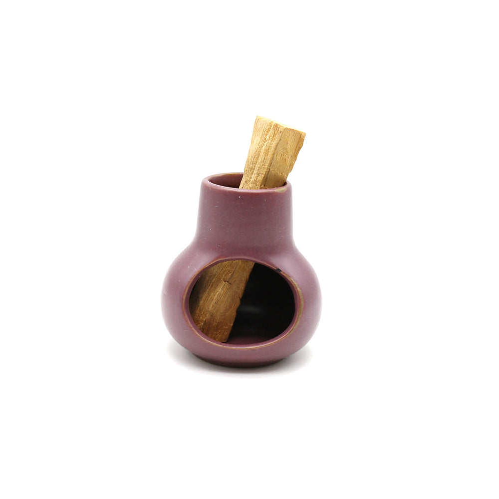 purple ceramic palo santo mini chimney with a palo santo stick in it.