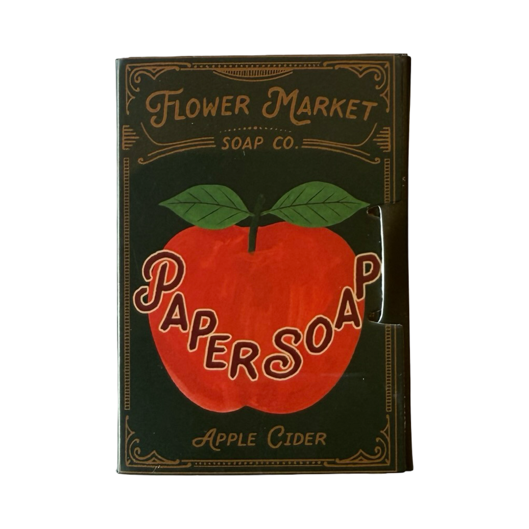 A vintage-style boxed soap product labeled 'Flower Market Soap Co.' with a large red apple graphic and the words 'Paper Soap' and 'Apple Cider' on a dark green background.