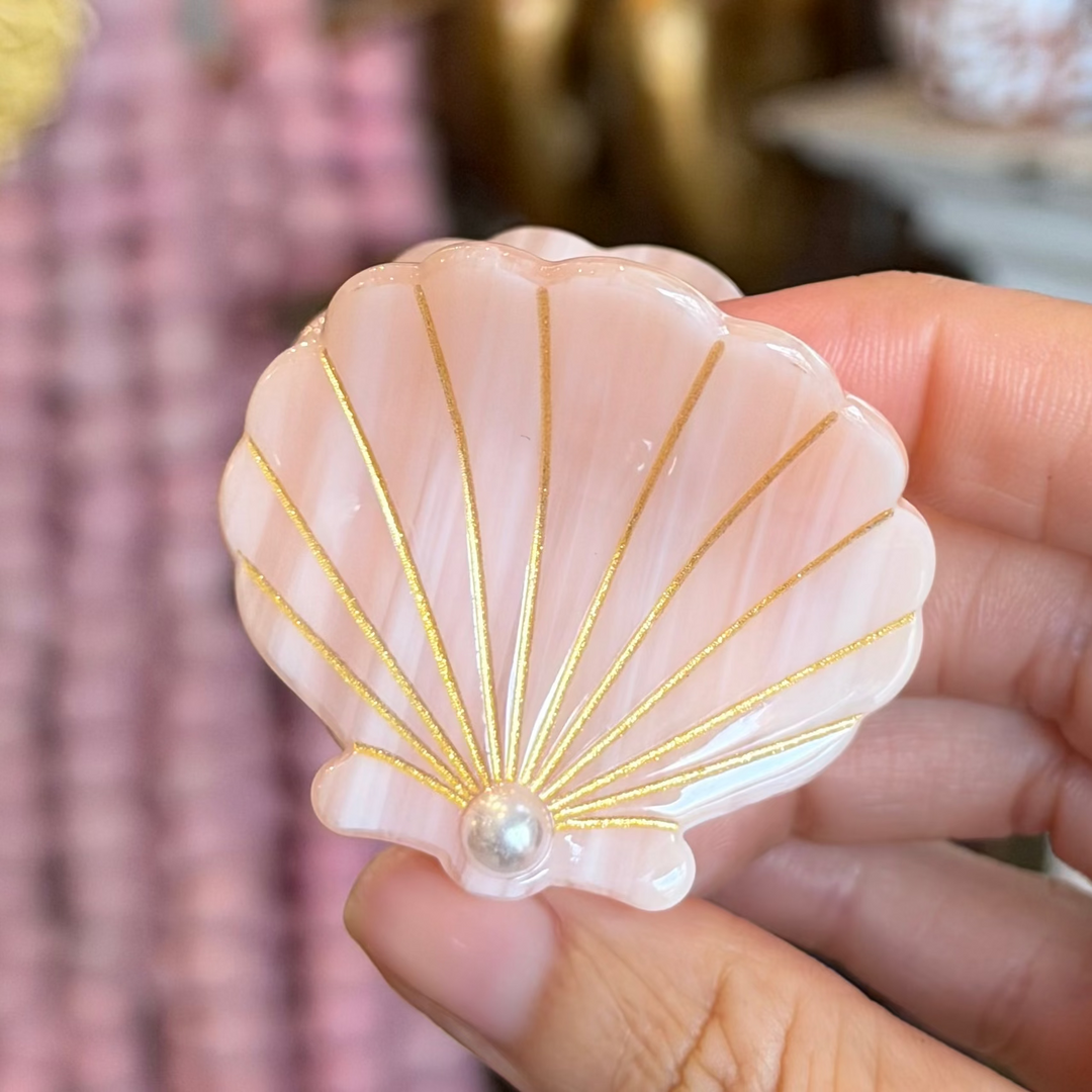 Peachy pink Iridescent seashell-shaped hair claw clip with gold detailing and a pearl accent.
