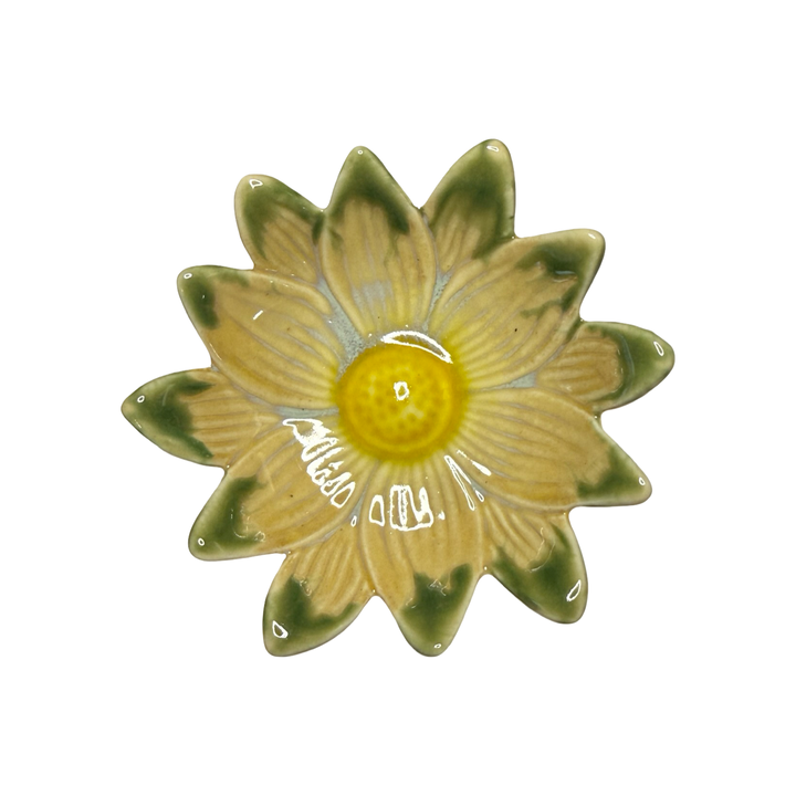 Stoneware daisy-shaped dish in beige with green tips and a yellow center glaze