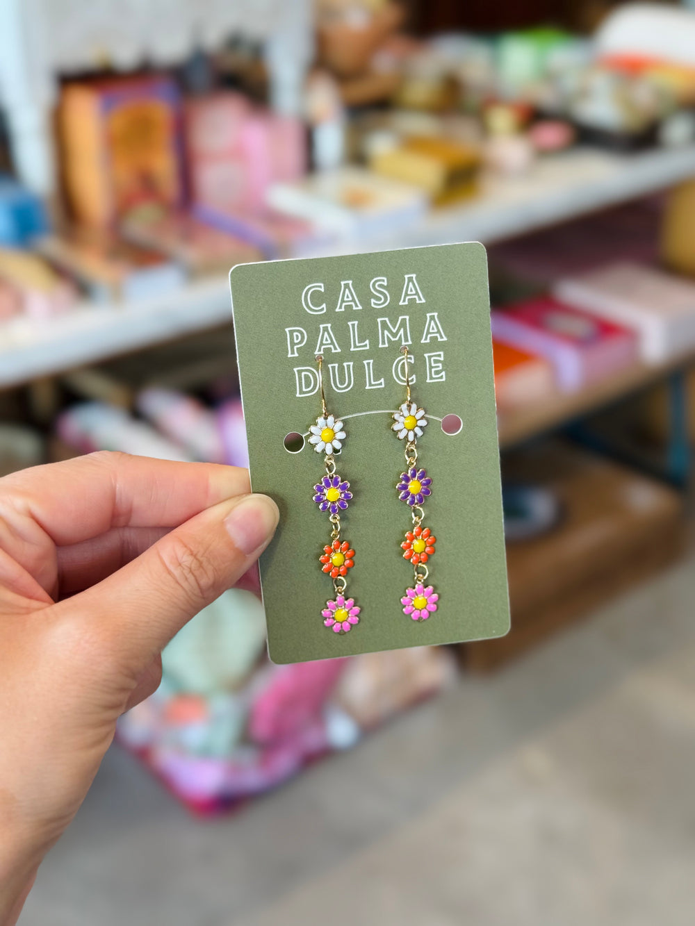 Hand holding a card with floral earrings and 'Casa Palma Dulce' branding.
