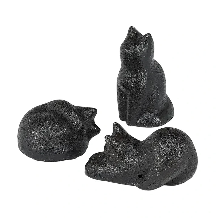 Three small cast iron black cat figurines, one curled up, one sitting upright, and one crouching.