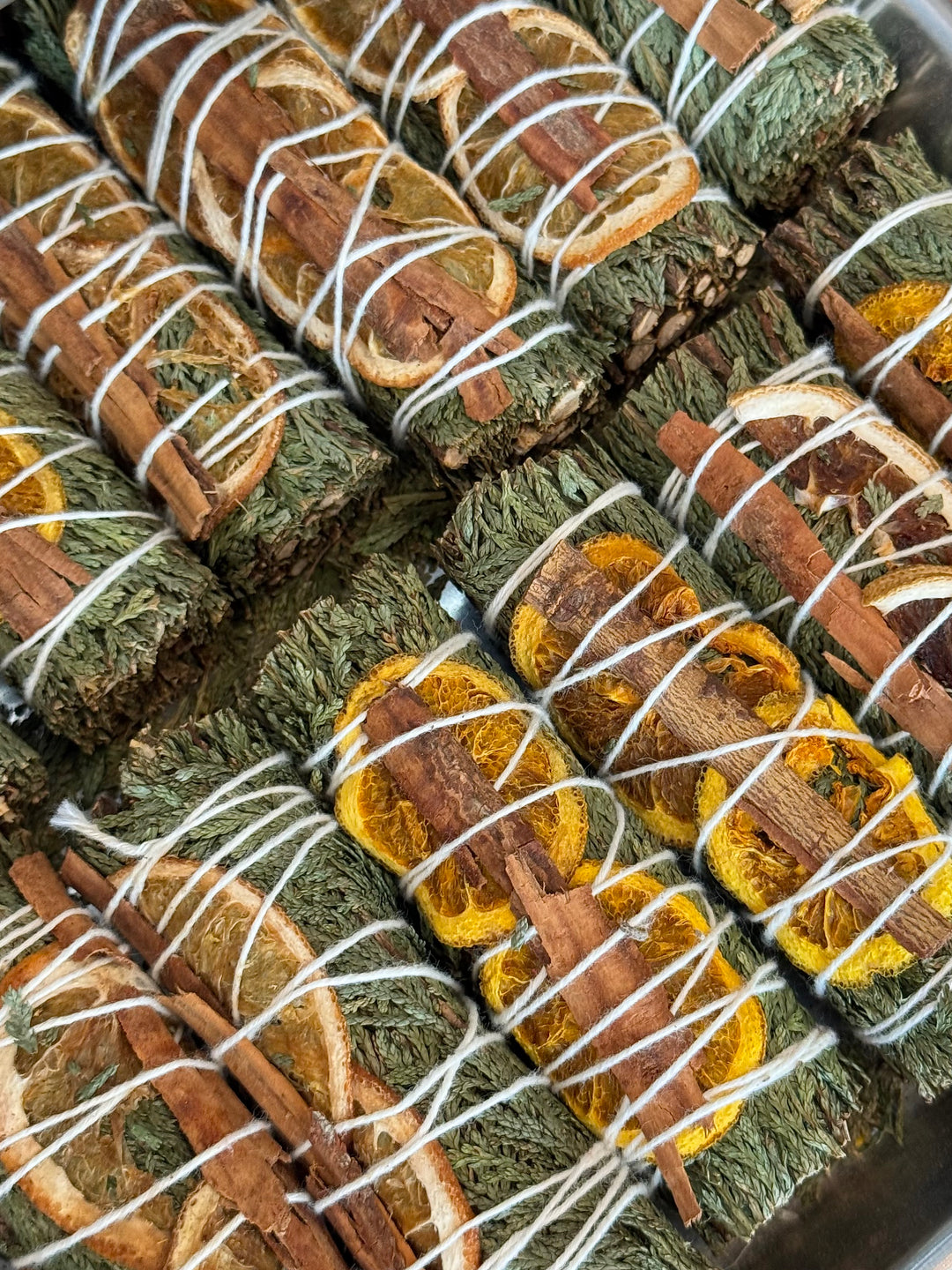 Page filled with bundles of rosemary with slices of oranges and cinnamon sticks wrapped in white twine