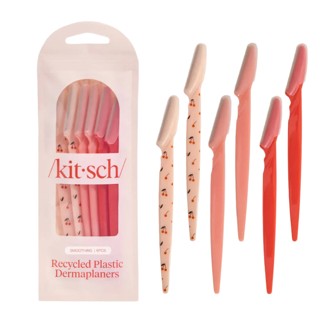 Six-pack of Kitsch dermaplaners in pink and red tones, with some handles decorated with small cherry patterns, shown alongside the packaging labeled “Recycled Plastic Dermaplaners.”