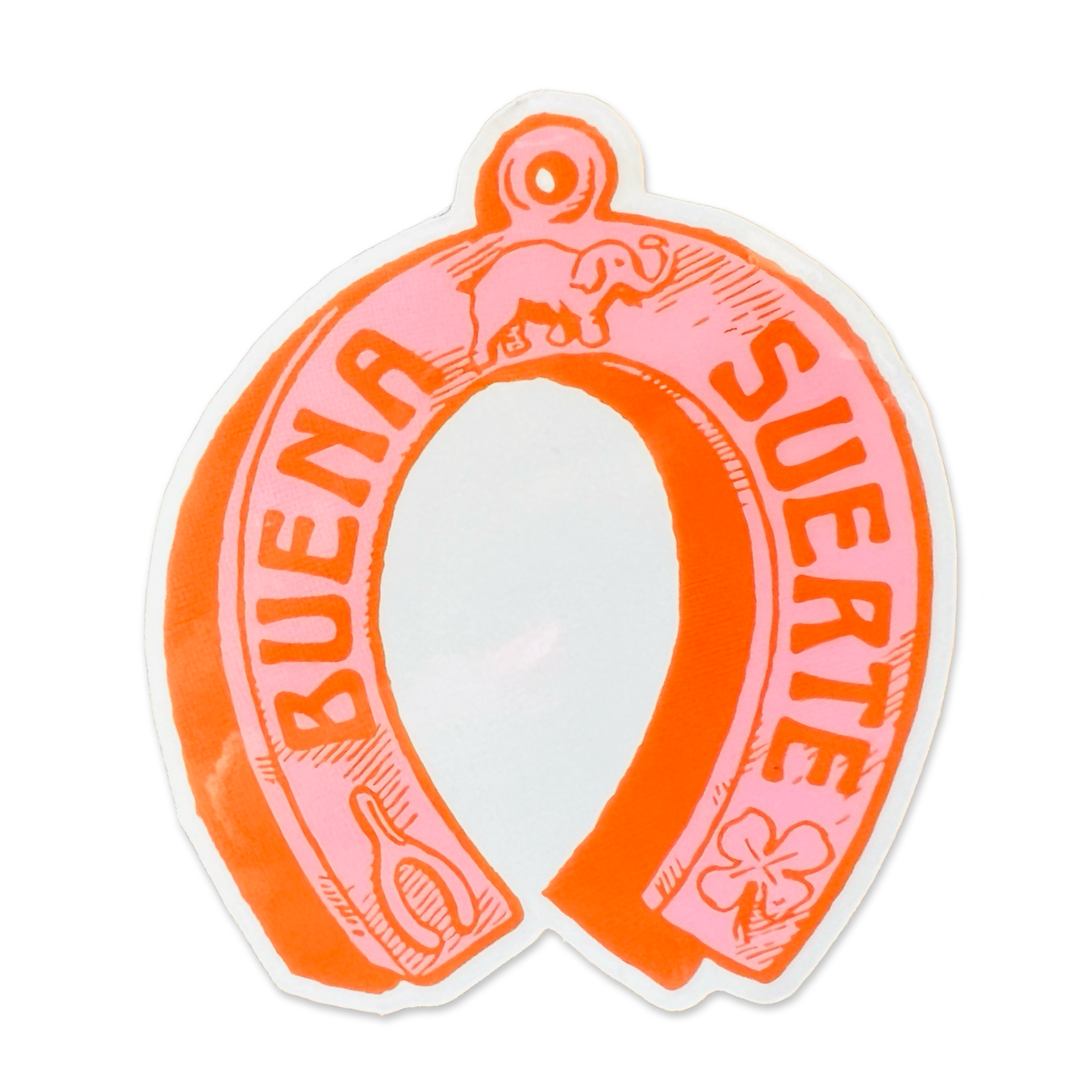 pink and orange horseshoe with images of an elephant, 3 leaf clover and wishbone with the phrase Buena Suerte in Orange lettering