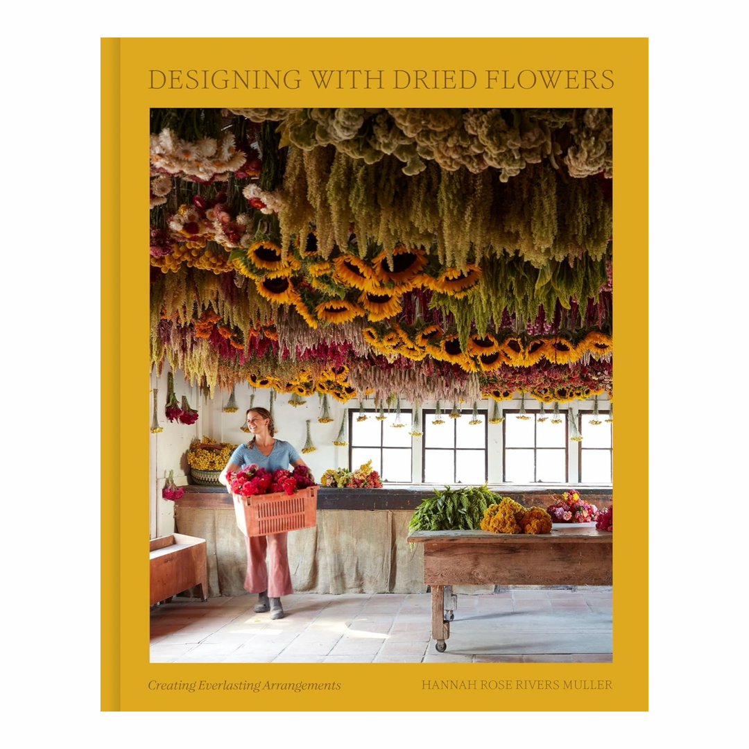 Designing with Dried Flowers book cover by Hannah Rose Rivers Muller, showing a woman holding a basket of flowers beneath a ceiling covered in hanging dried blooms"