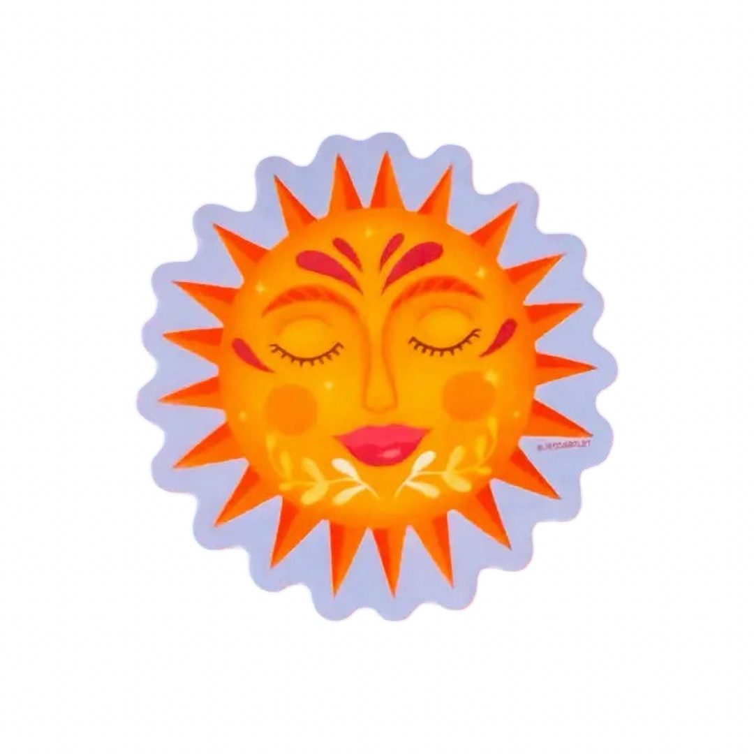A circular sun sticker with a serene human face, closed eyes, rosy cheeks, and pink lips. Golden yellow and orange rays radiate outward, with red decorative accents on the forehead and small leaf sprigs below the chin, framed by a wavy lavender border.