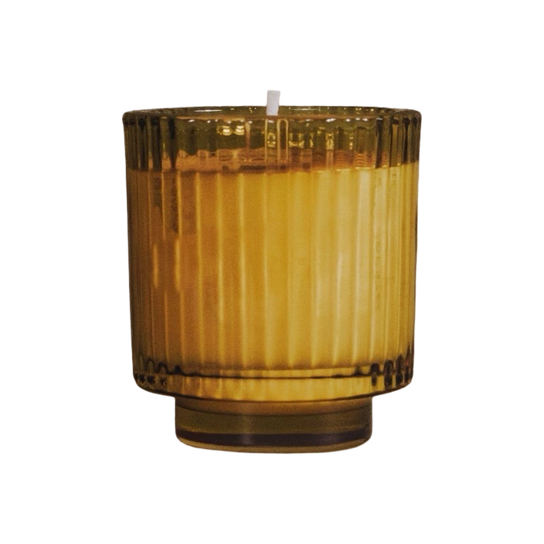 candle in a amber ribbed glass vessel with a footed base.