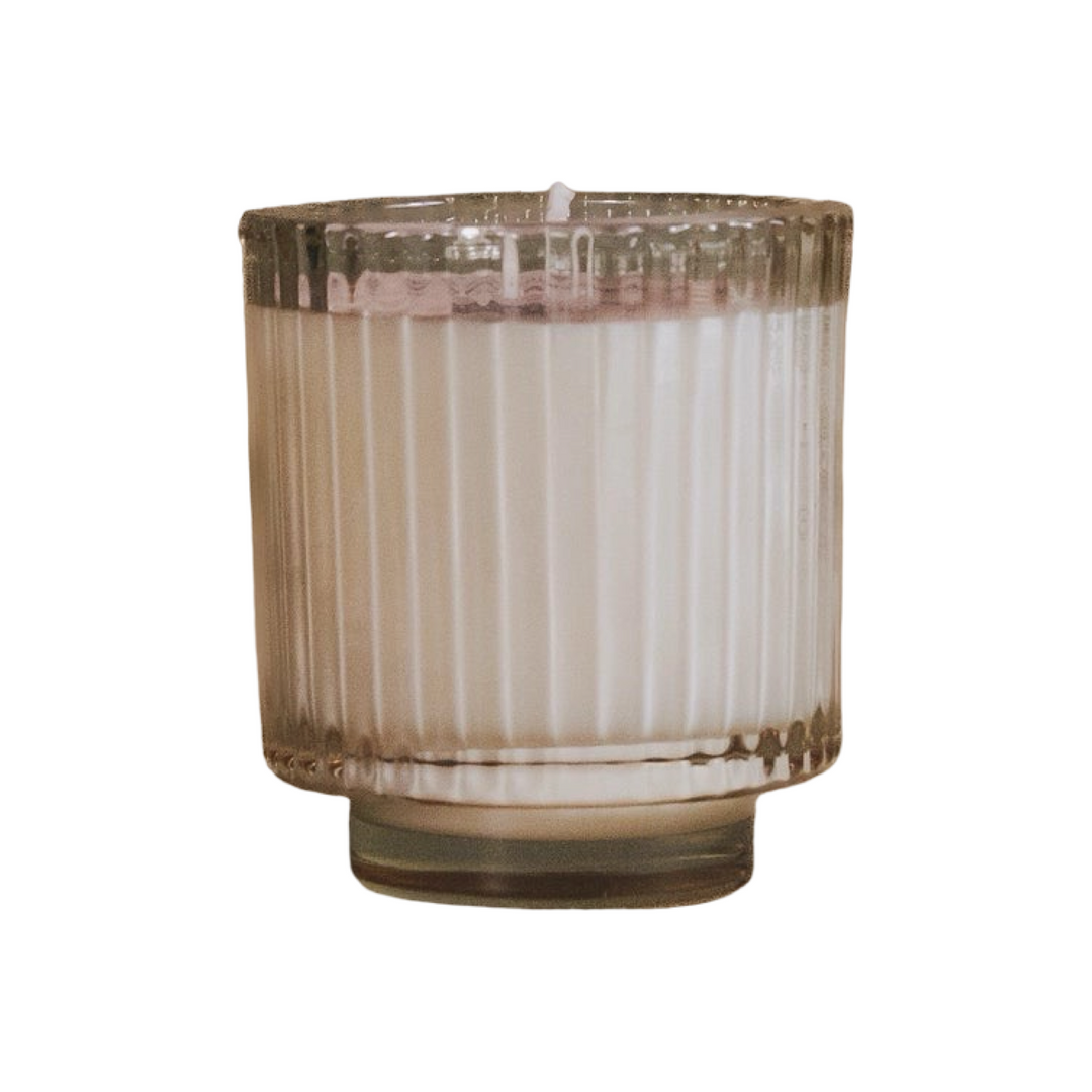 candle in a clear ribbed glass vessel with a footed base.