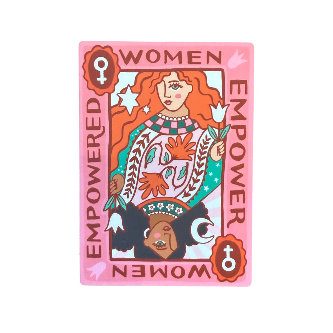Rectangular sticker resembling a playing card, featuring two mirrored illustrations of empowered women—one with flowing red hair and one with curly black hair—surrounded by the phrase “Empowered Women Empower Women” on a pink and red background.