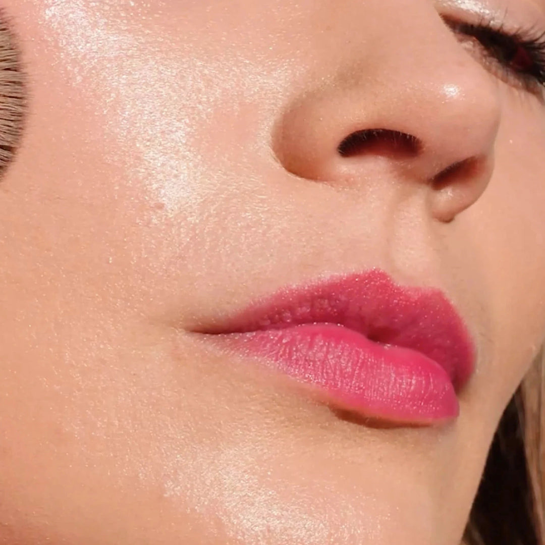 an image of a woman with pink lips applied blush with a brush