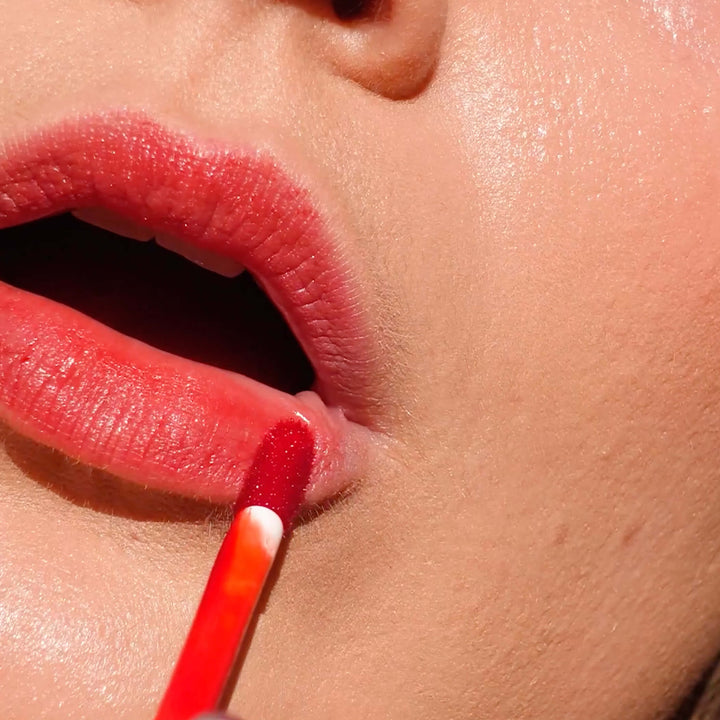 close up of a pair of lips with lip tint being applied to them.