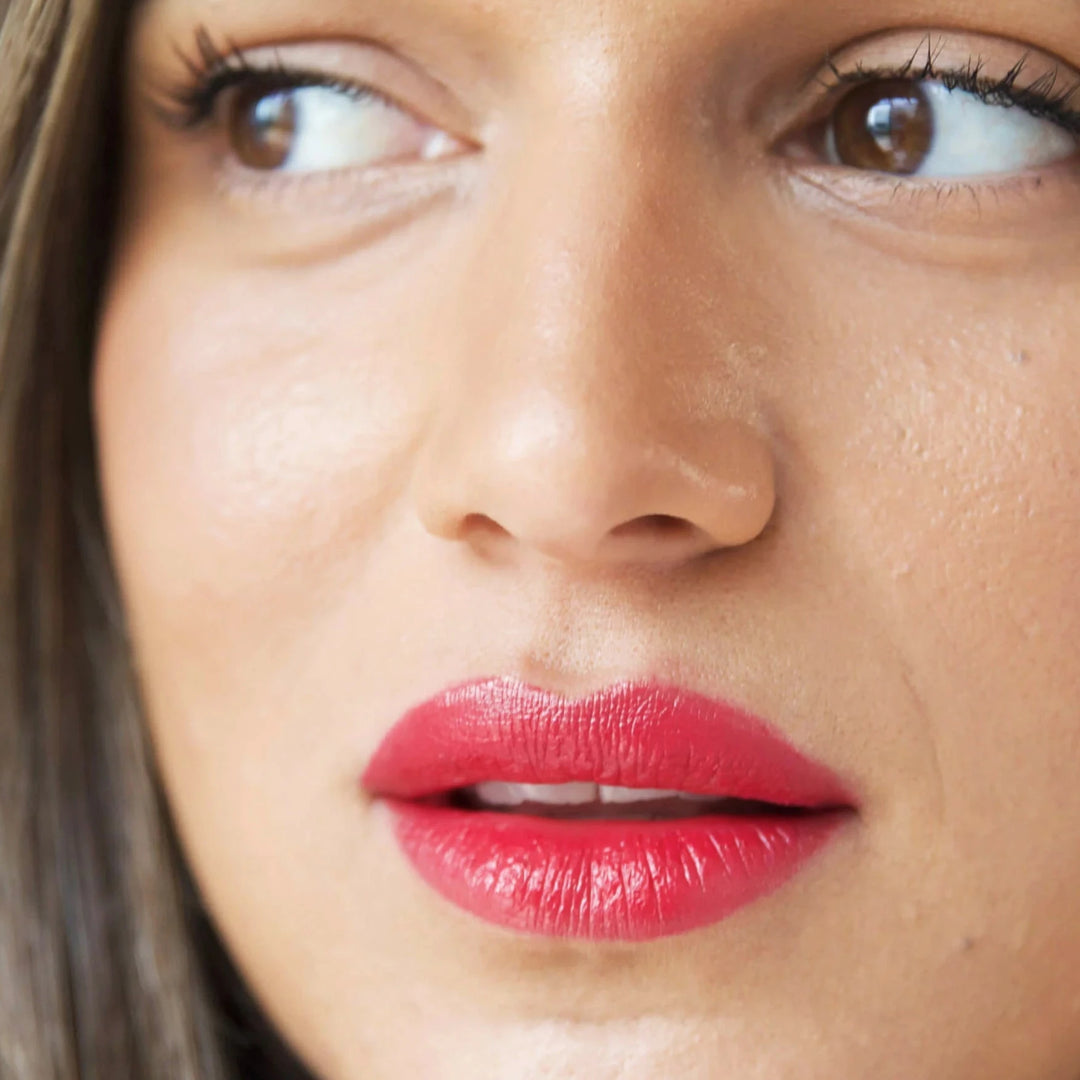a close up of a woman's face wearing fuschia lip stick