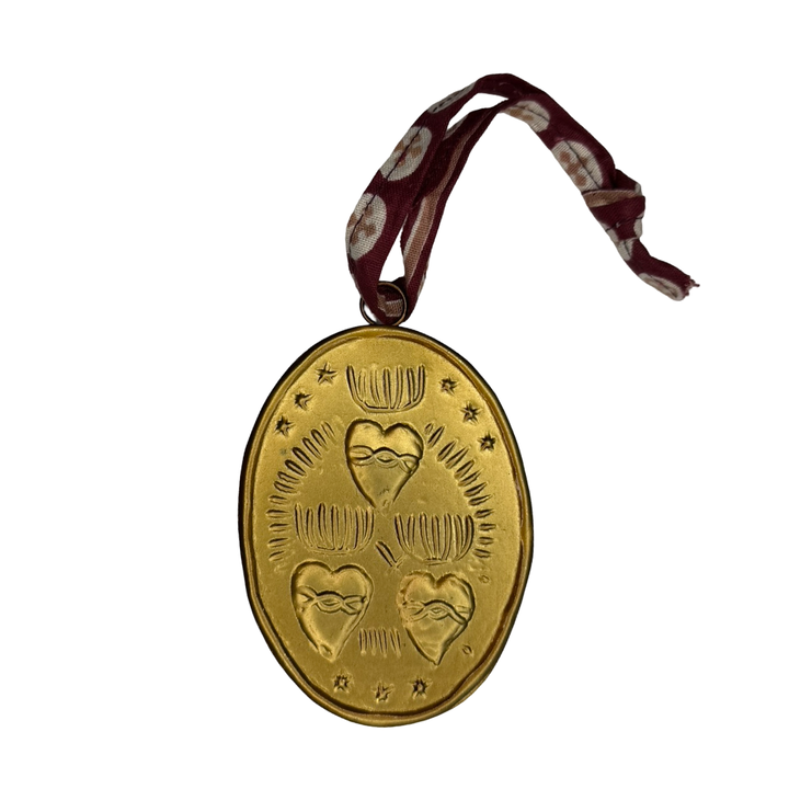 Three embossed sacred hearts on a oval gold medallion with brown ribbon hanger.