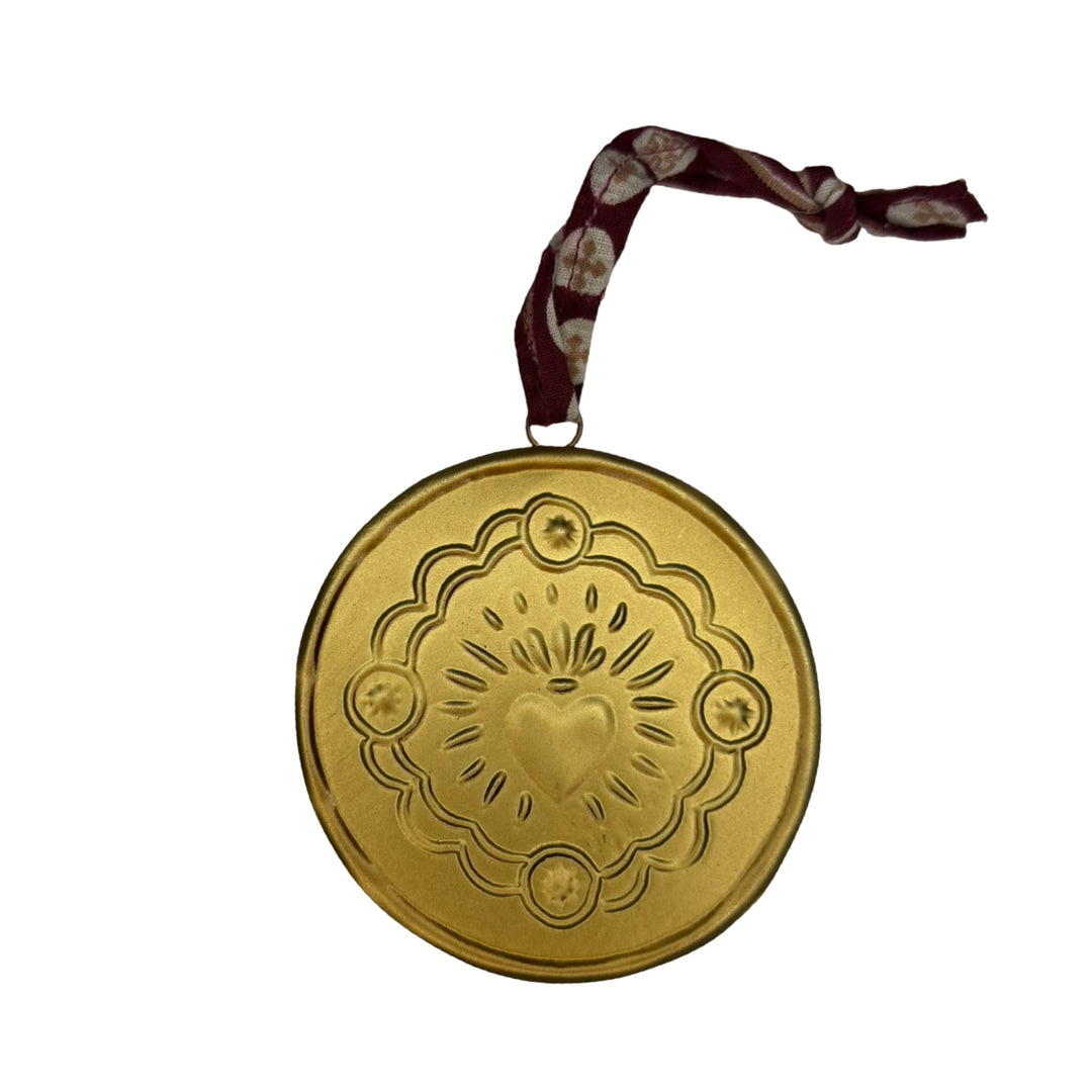 Gold medallion with brown tie features sacred heart design.