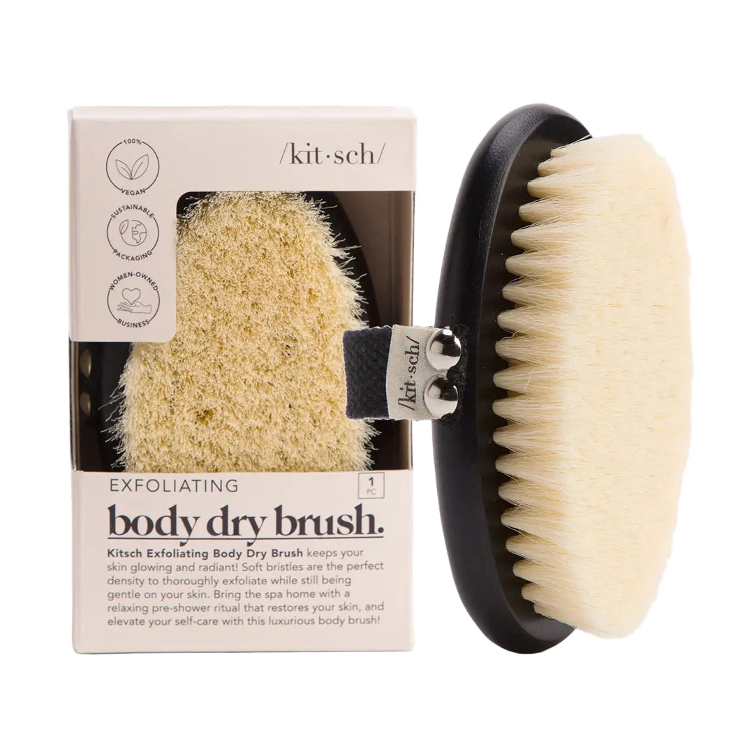 Kitsch Exfoliating Body Dry Brush displayed next to its beige box packaging; the oval brush has cream bristles, a black base, and a fabric hand strap.