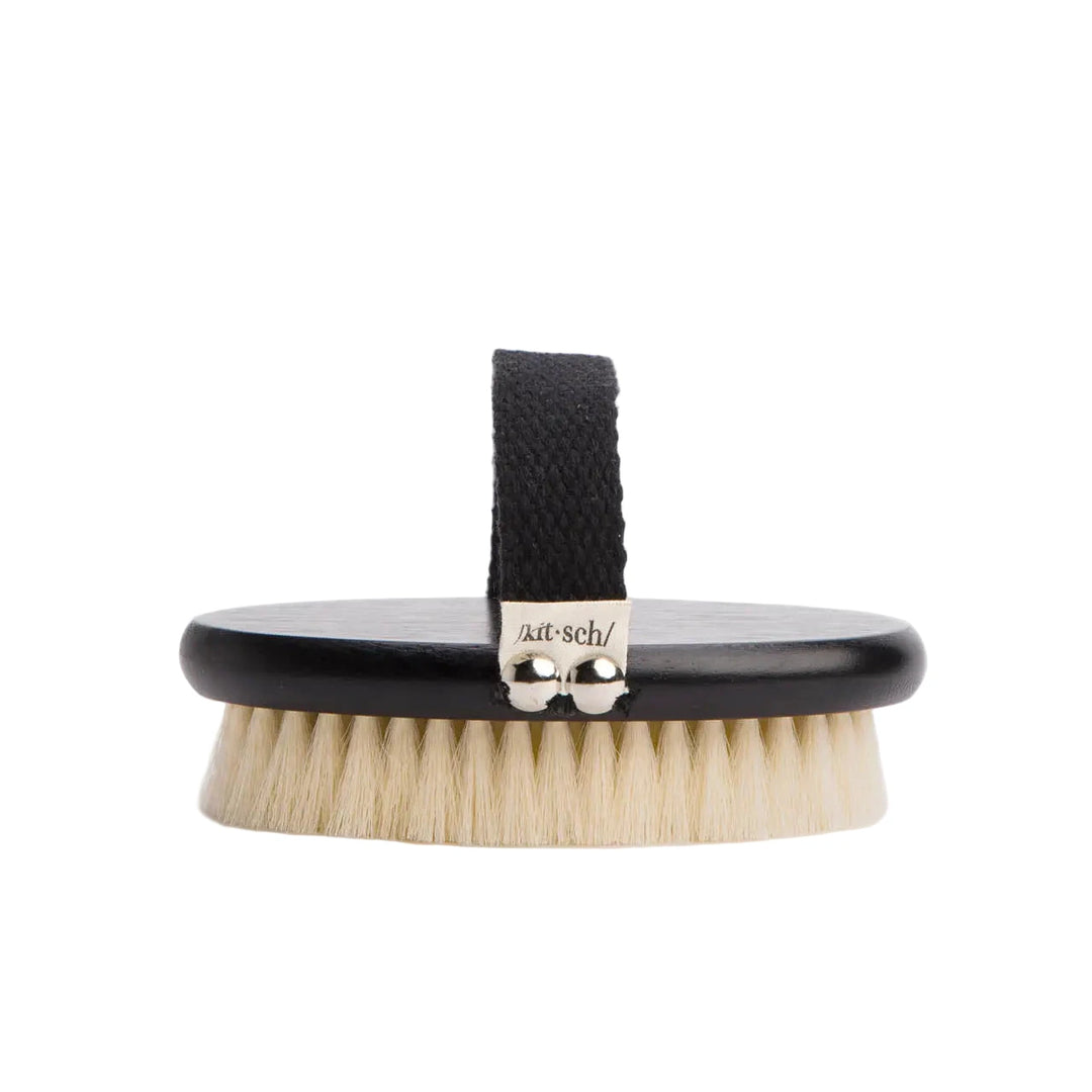 Oval black-handled dry brush with cream bristles and an adjustable fabric hand strap