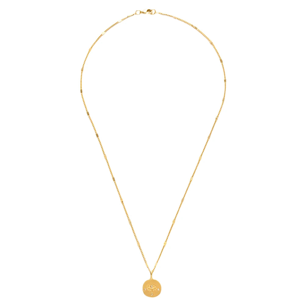 A gold Eye of Protection Necklace featuring a round pendant with an engraved eye design and crystal accents. The pendant hangs from a delicate gold chain with subtle decorative links, 