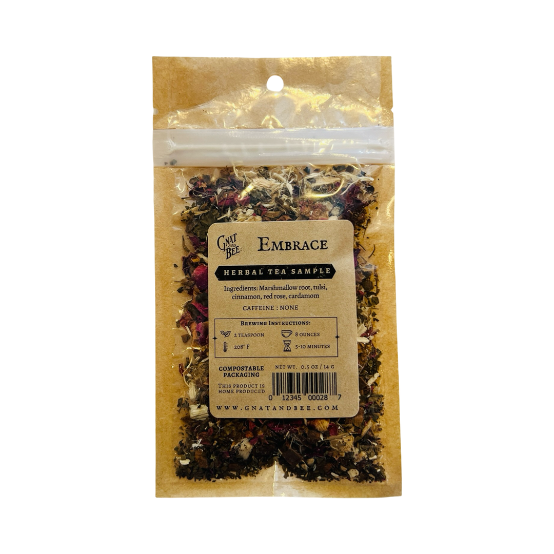 A compostable pouch of Gnat and Bee's "Embrace" Herbal Tea Sample, featuring a blend of marshmallow root, tulsi, cinnamon, red rose, and cardamom. The kraft paper label provides brewing instructions and indicates that the tea is caffeine-free.