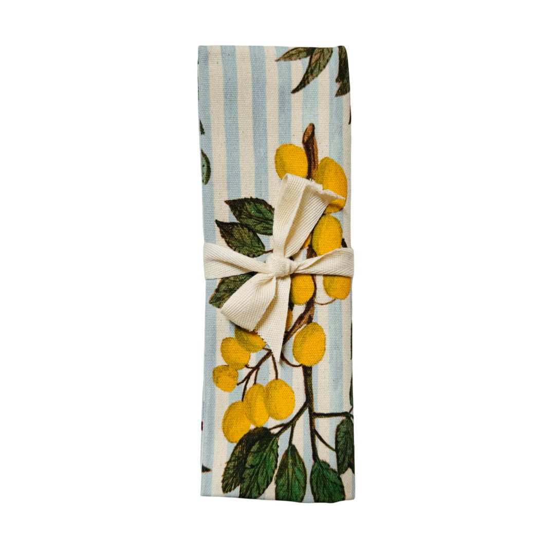 Tea towel featuring illustrated botanical branches with fruits and berries arranged on a striped background with a decorative border folded in half and tied with a ribbon.