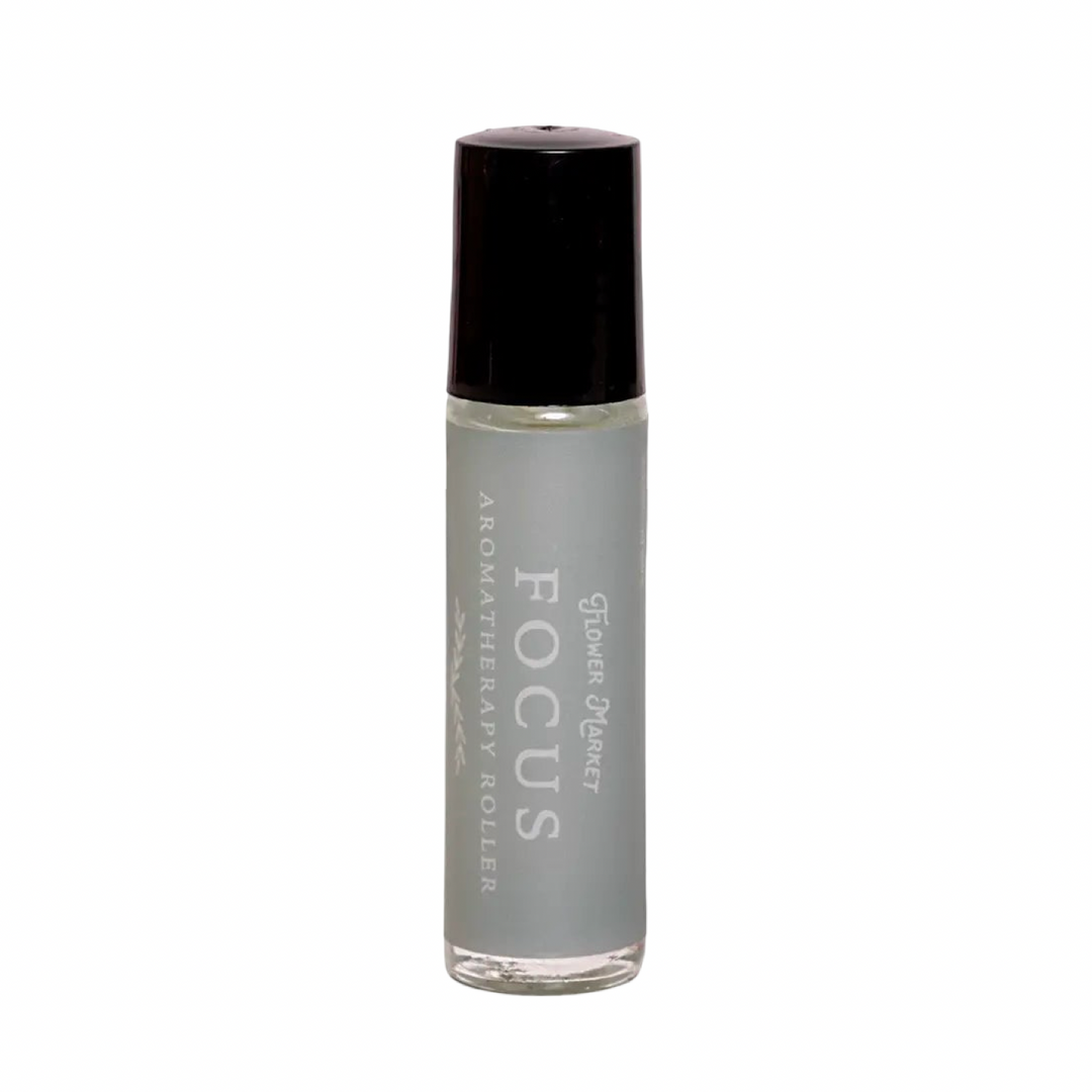 A small glass aromatherapy roller bottle labeled Focus by Flower Market with a green gemstone roller ball and a soft gray label.