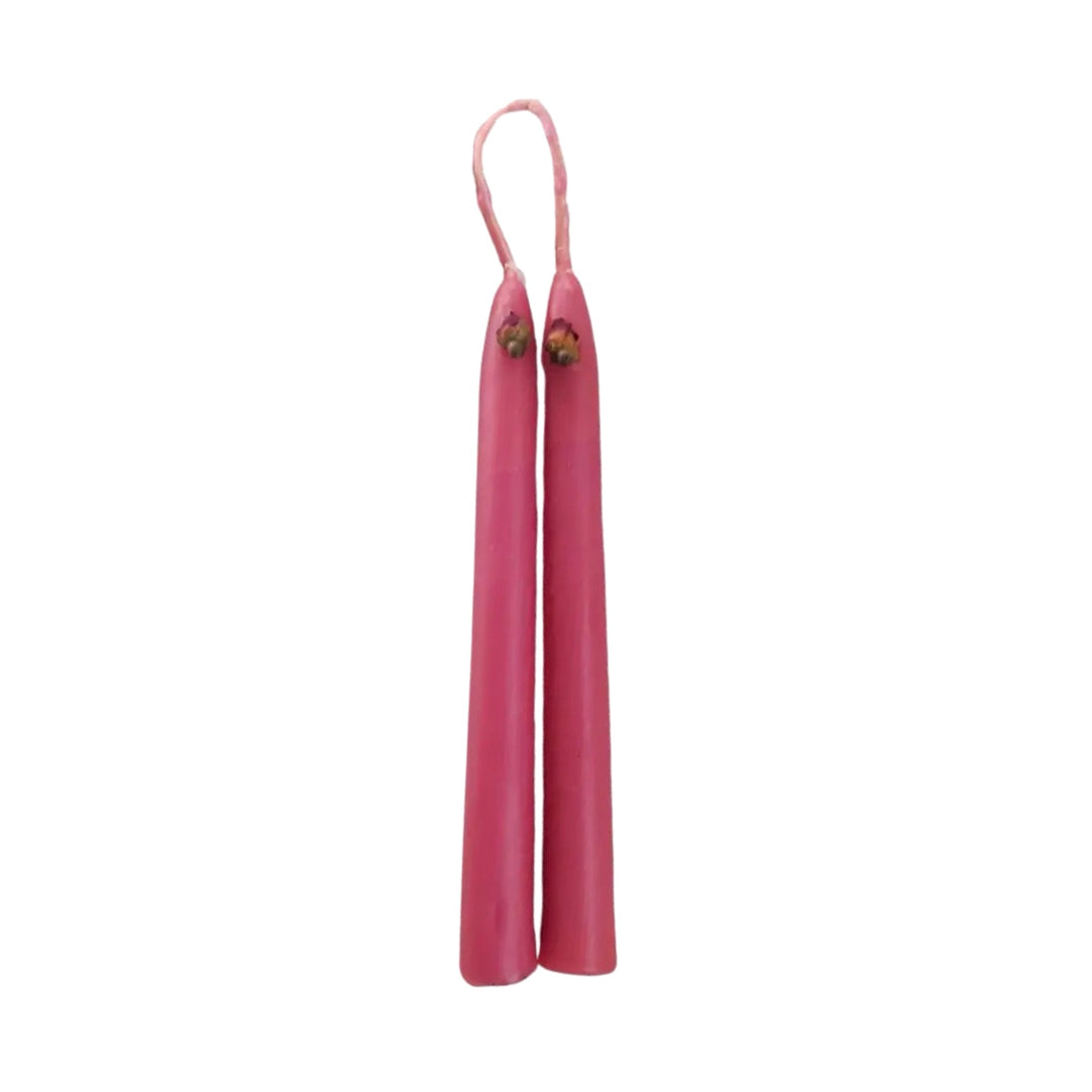 A pair of hand-dipped pink taper candles connected by a wick loop, showcasing a rustic and artisanal design.