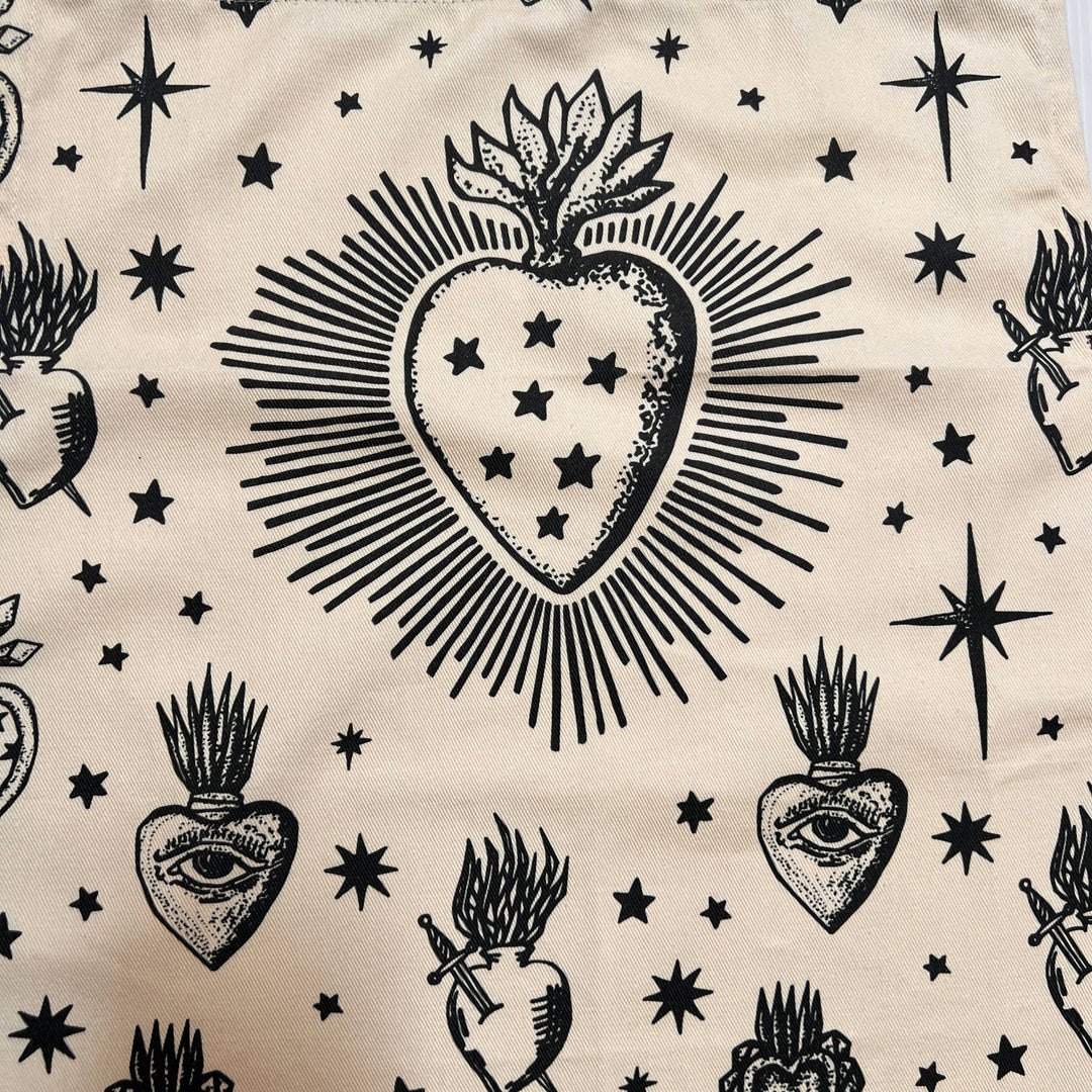 close up view of a cream apron with images of various sacred hearts