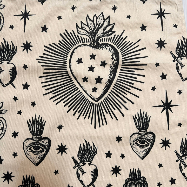 close up view of a cream apron with images of various sacred hearts