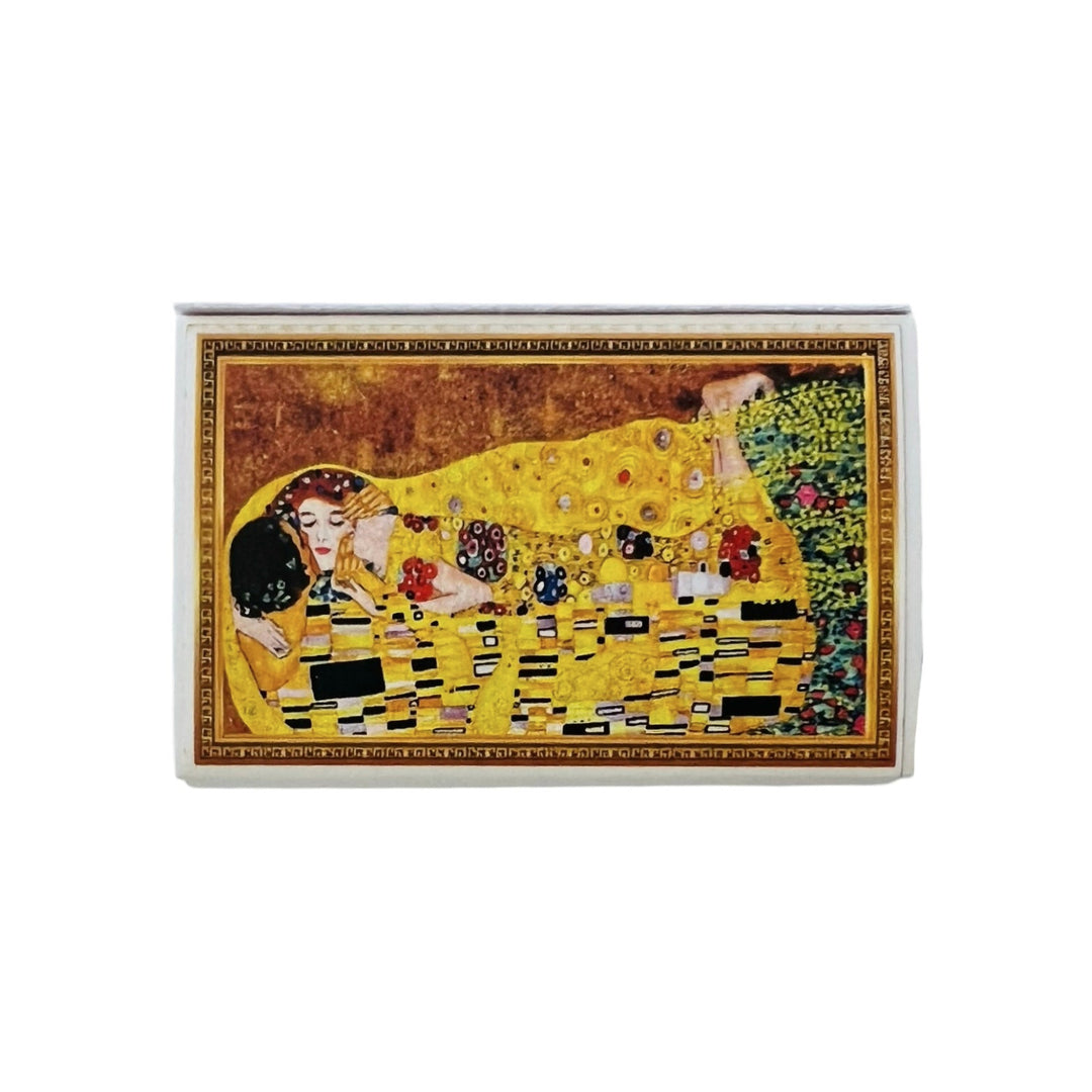 A matchbox featuring Gustav Klimt's "The Kiss" painting on the cover. The artwork showcases a romantic embrace in golden hues with intricate patterns, set against a rich background.