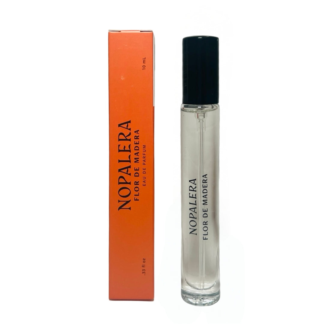 clear 10ml jar with a black top flanked by a orange branded box of Flor De Madera Nopalera perfume