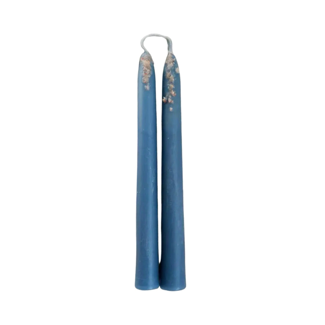 A pair of hand-dipped blue taper candles connected by a wick loop, showcasing a rustic and artisanal design.