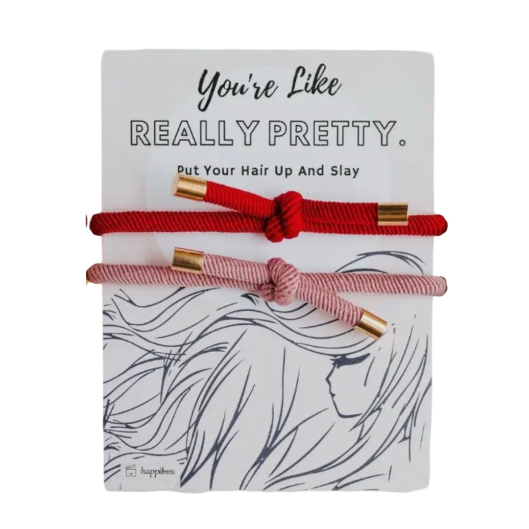 hair tie set features two elegant corded ties in vibrant red and soft pink, each accented with gold metal tips on a white branded backing.