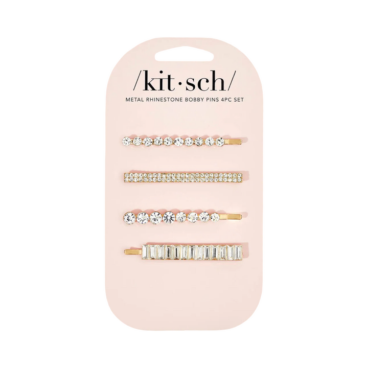 Four gold metal bobby pins with assorted rhinestone designs on a branded display card.