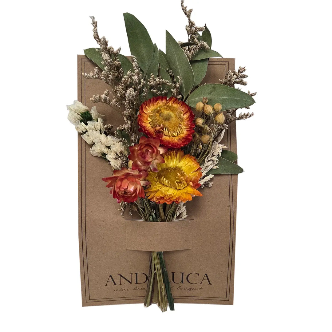 Dried mini bouquet of golden and coral strawflowers, white statice, sea lavender, eucalyptus leaves, and flax pods, tucked into a pocket on a kraft paper card.