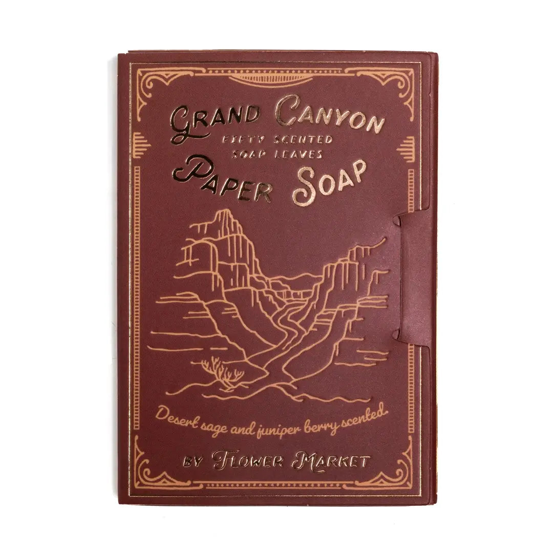 A burgundy book style package of Grand Canyon paper soap leaves by Flower Market, featuring gold foil canyon illustrations and desert sage and juniper berry scent, containing 50 soap leaves.