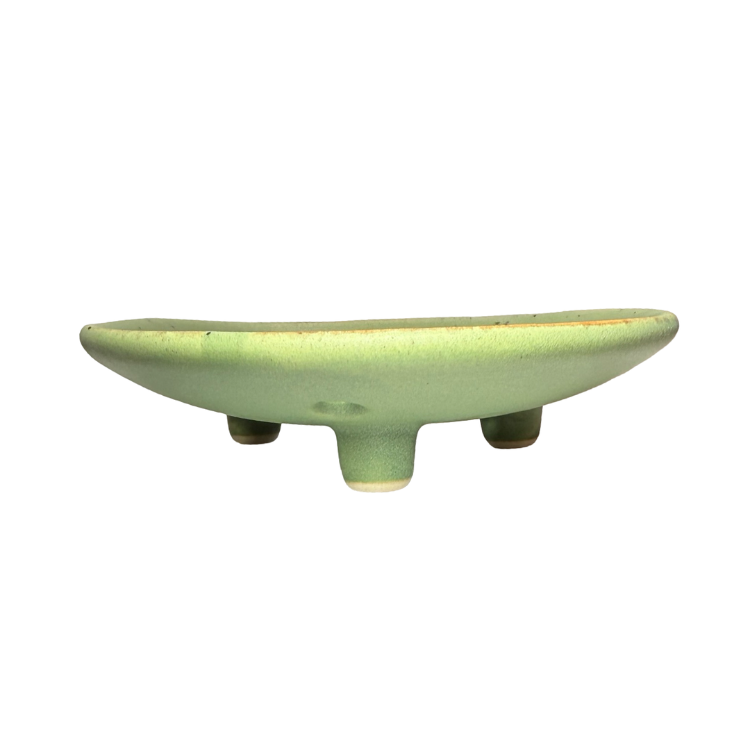 side view of a round ceramic footed soap dish with perforated drainage holes, shown in green.