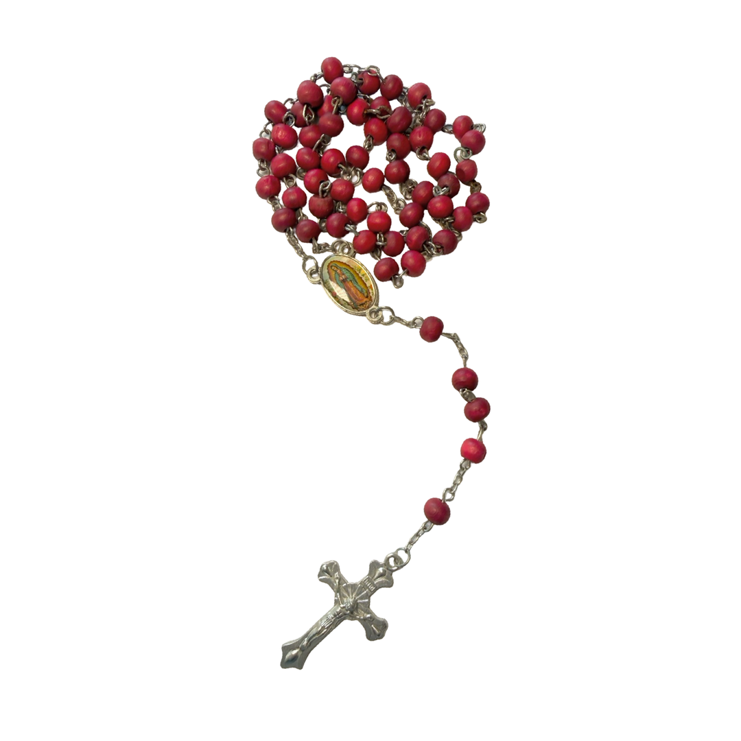 A Catholic rosary with red wooden beads on a silver-tone chain, featuring a colorful oval Our Lady of Guadalupe medal centerpiece and a silver-tone crucifix.