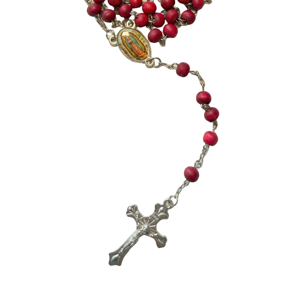 close up of a Catholic rosary with red wooden beads on a silver-tone chain, featuring a colorful oval Our Lady of Guadalupe medal centerpiece and a silver-tone crucifix.