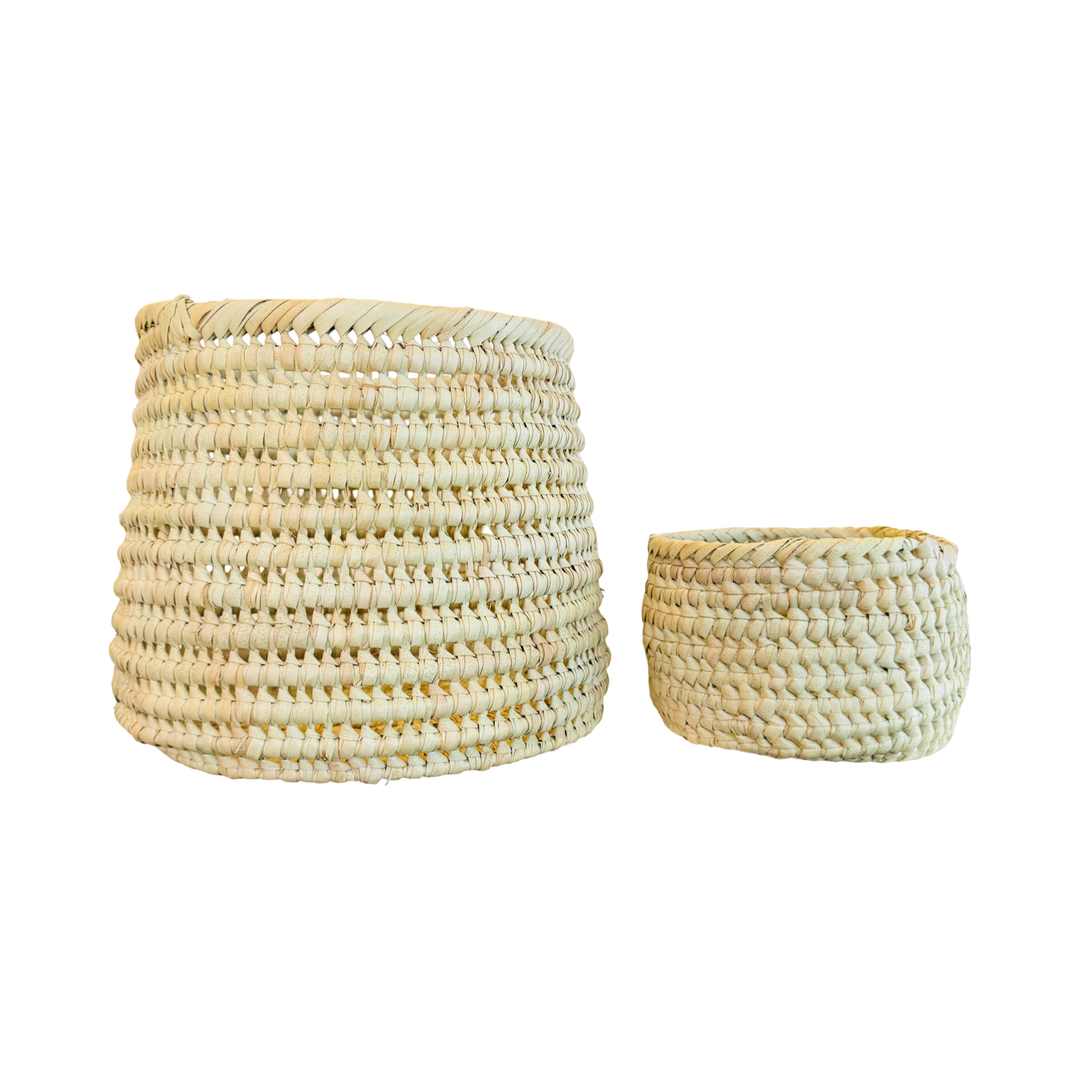 A set of round handwoven natural palm leaf baskets with one bigger than the other.