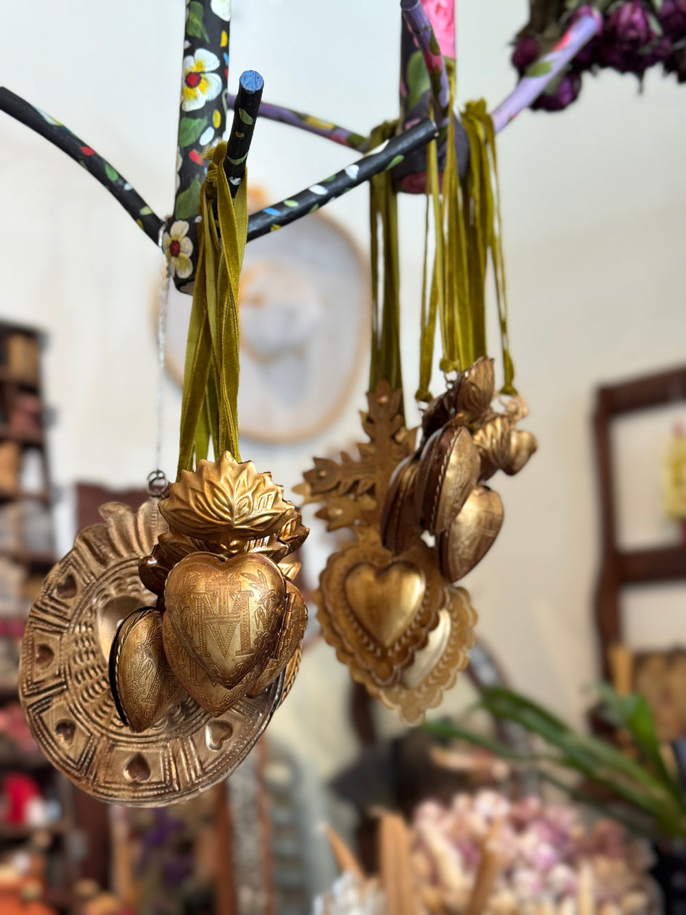 Decorative heart-shaped brass pendants hanging from a branch with a blurred background