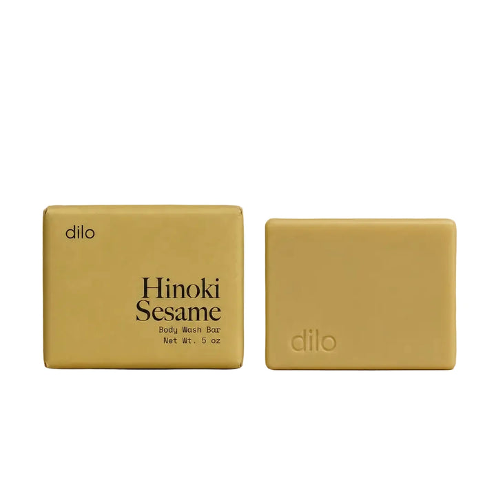 Dilo Hinoki Sesame body wash bar with golden yellow packaging shown alongside the unwrapped soap bar.