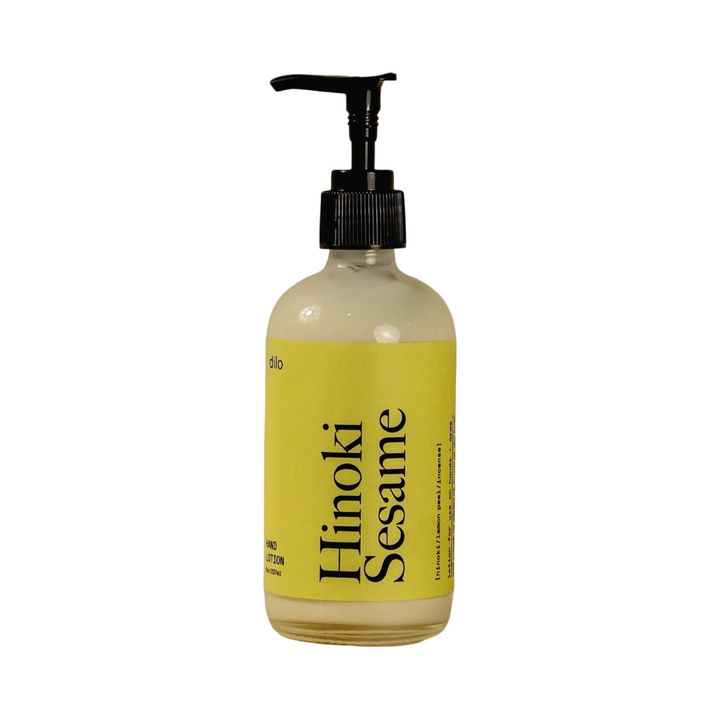 8 oz clear glass pump bottle of Dilo Hinoki Sesame Hand Lotion with a bold yellow label and black typography