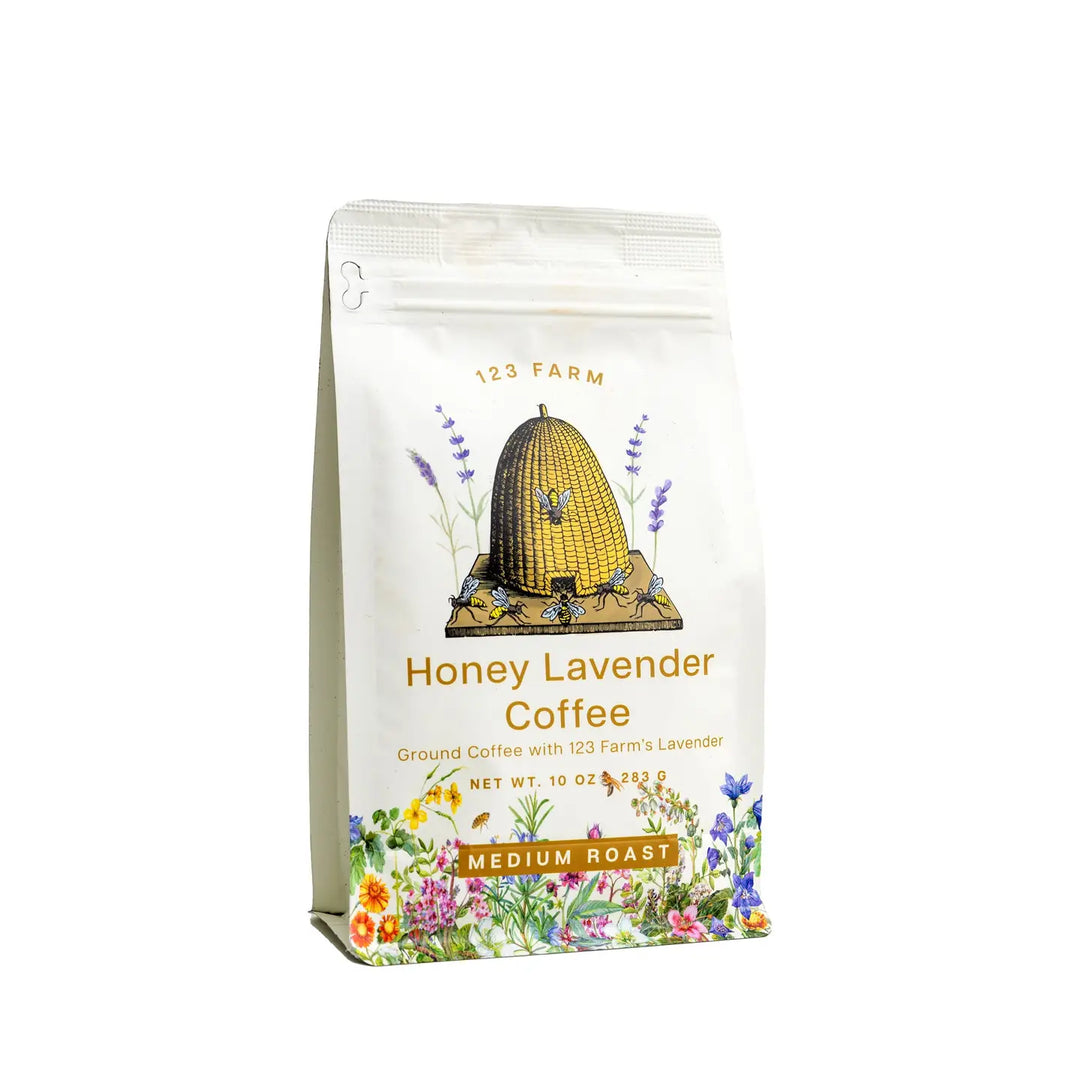 A pack of Honey Lavender Coffee by 123 Farm, featuring a white bag with an illustration of a bee on a lavender flower, and text describing the product as medium roast ground coffee infused with farm-fresh lavender and natural honey.