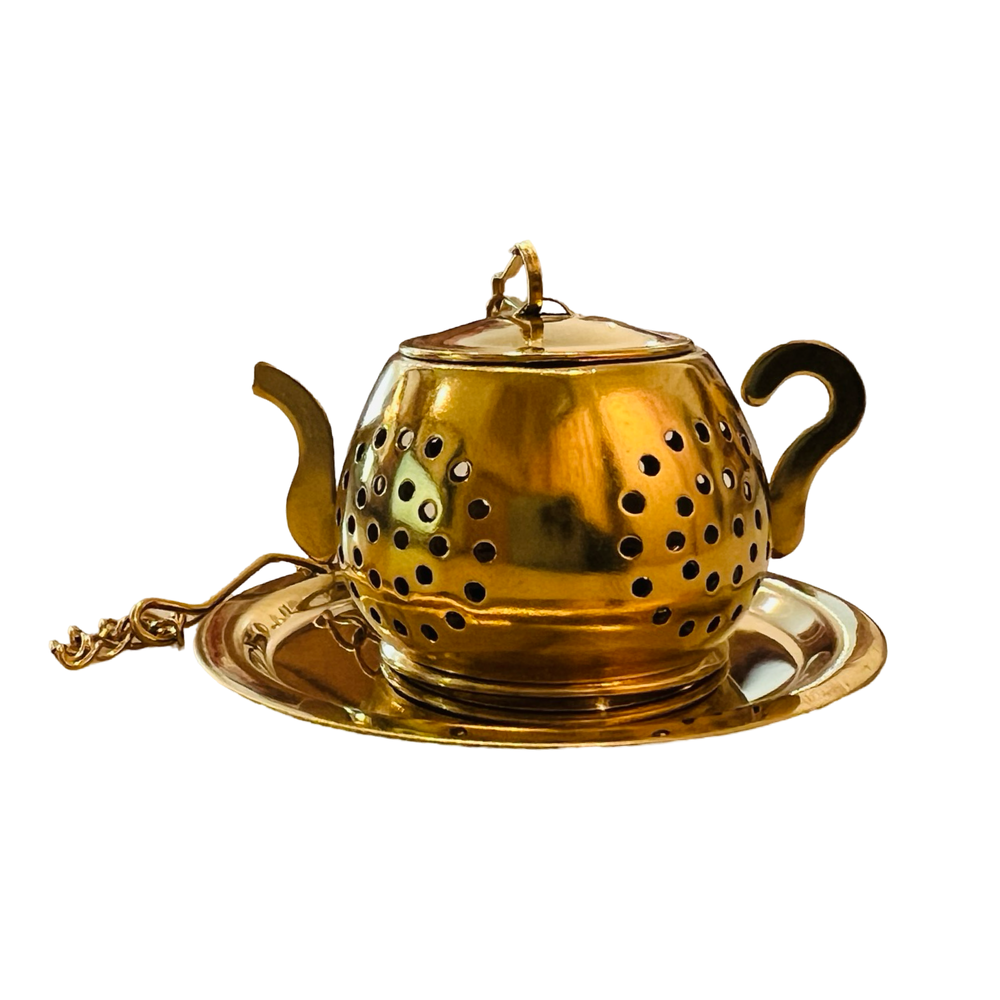  a gold teapot-shaped tea infuser. It features a perforated design and has a small chain 