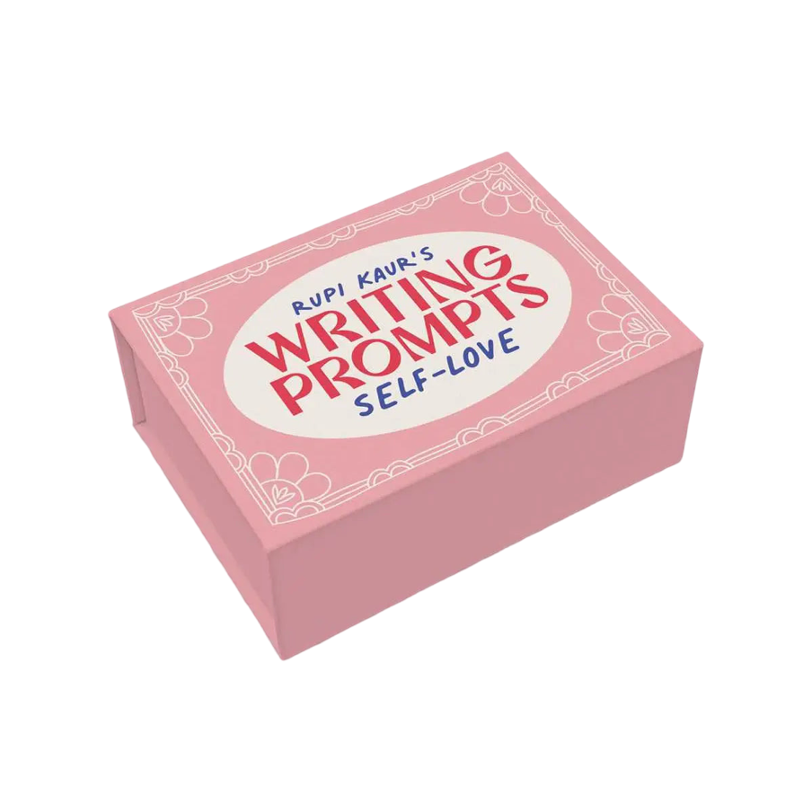 A pink box featuring the title "Rupi Kaur's Writing Prompts: Self-Love" in red and blue text, surrounded by a delicate floral border. The box is designed to inspire self-reflection and creative writing.