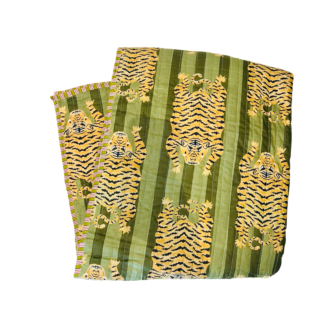 a blanket folded in quarters with a dual green and tiger-striped pattern.