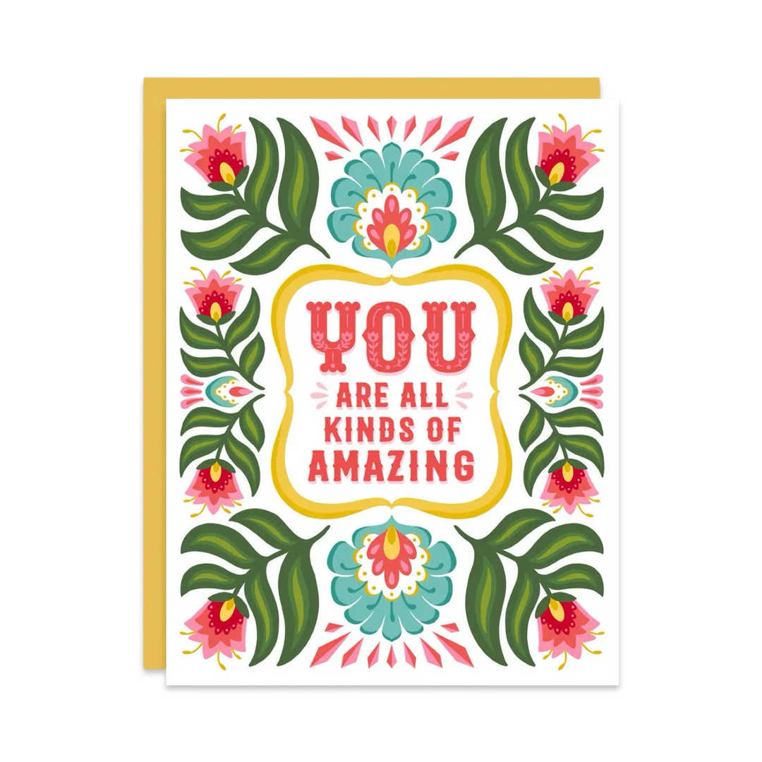 Greeting card with colorful floral and leaf patterns surrounding the message 'YOU ARE ALL KINDS OF AMAZING' in bold, decorative font. The card features vibrant green, pink, and teal tones with a yellow border and envelope.