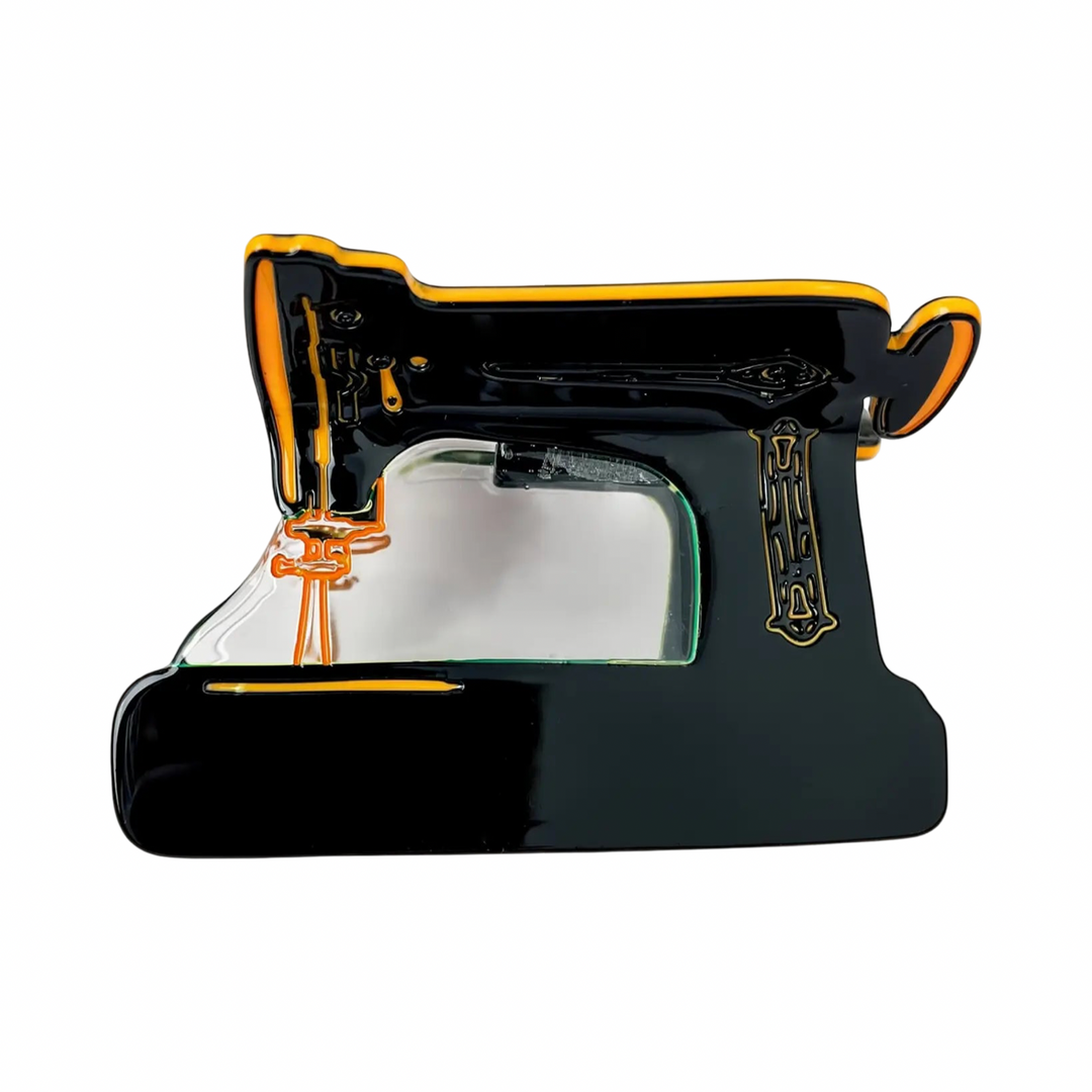 Black vintage sewing machine claw clip with golden orange trim and ornate gold detailing.